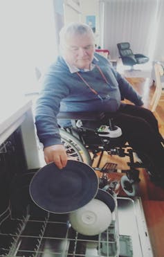 Man in power wheelchair reaches to unload dishwasher drawer