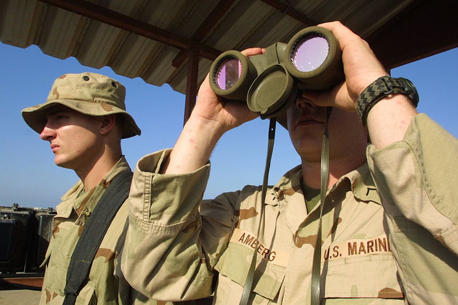 American marines, one holds binoculars to his face.