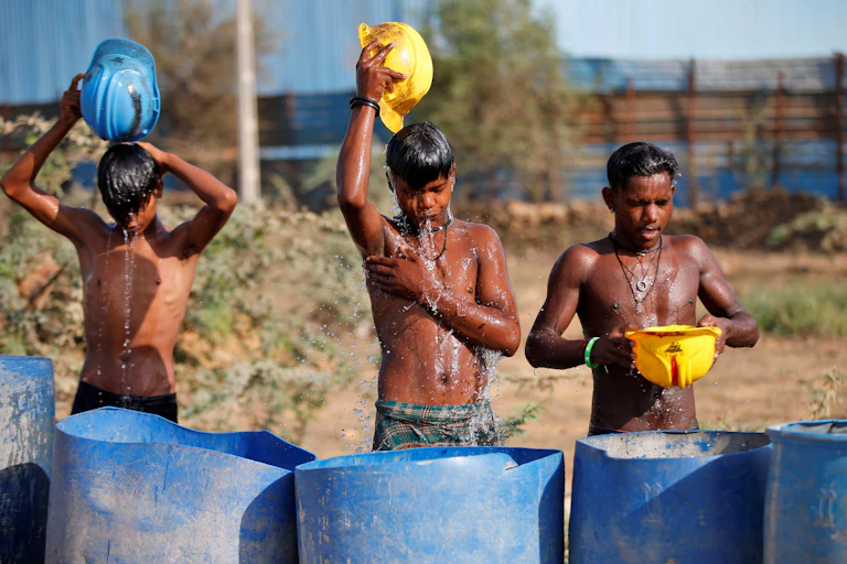 Three young men poor water over their heads with helmets.