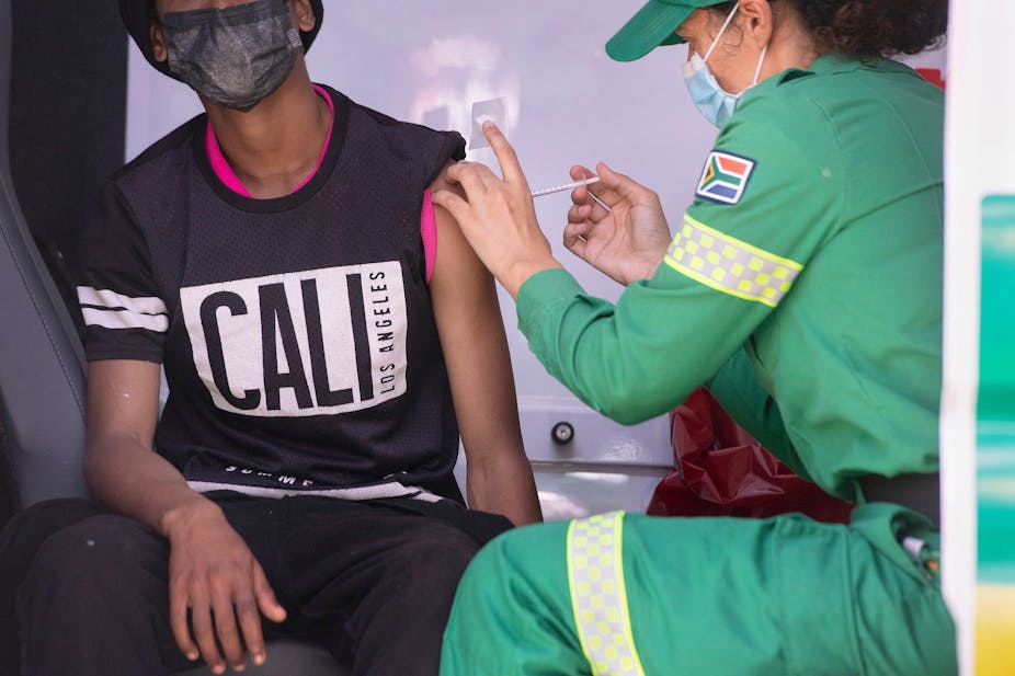 A man getting vaccinated by a health worker. Both of them are wearing a face mask.