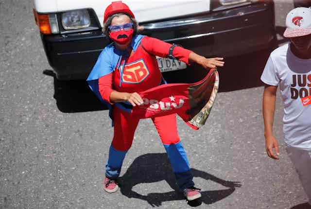 A child wearing a blue cape and red costume.