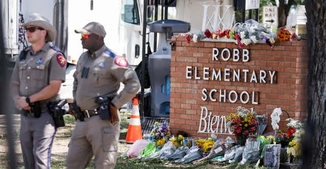 Patrol officers standing near a memorial outside the Robb Elementary School in Uvalde, Texas