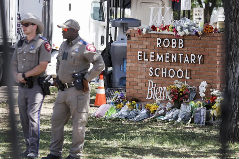 Patrol officers standing near a memorial outside the Robb Elementary School in Uvalde, Texas