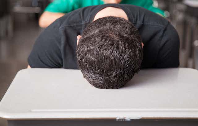 Boy sitting at desk puts his head on the table