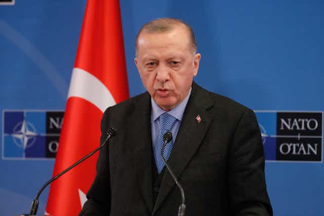 Turkish president Recep Tayyip Erdogan delivers a speech at Nato HQ, in frontof a Turkish flag.