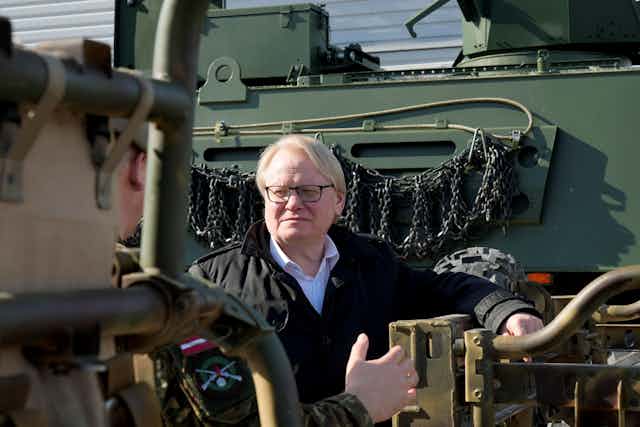 A man wearing glasses looking at military equipment.