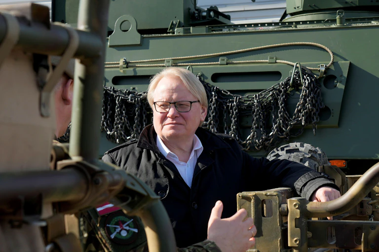 A man wearing glasses looking at military equipment.