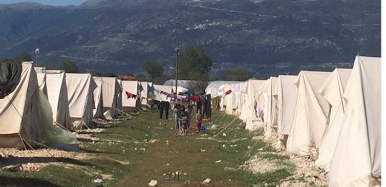 Two long rows of white tents in a refugee camp