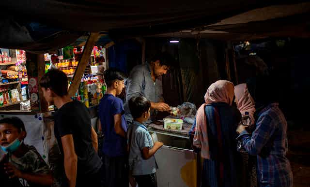 Refugees buy ice cream in a makeshift shop