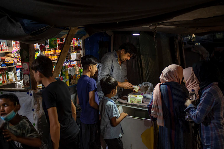 Refugees buy ice cream in a makeshift shop