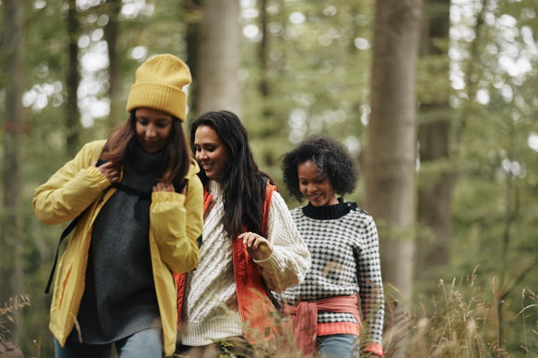Three women walking in the woods.