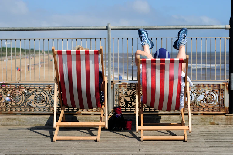 Rear view of couple relaxing on deck chairs.