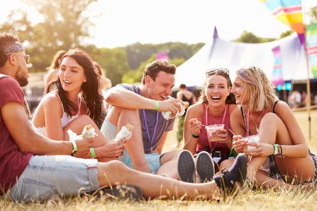 Young people eating and socialising at a music festival.