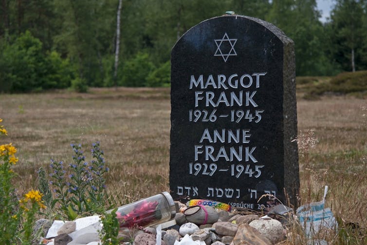 A gravestone for Anne and Margot Frank in a field.