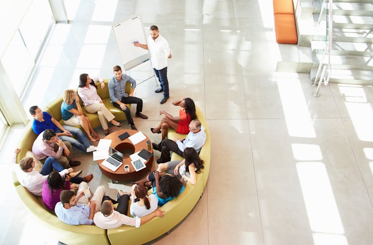 An overhead shot of a group meeting in an open-plan office.