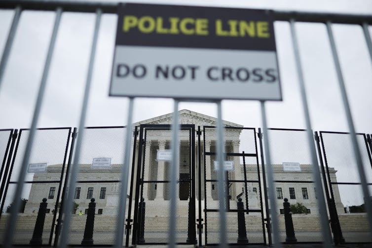 A big fence with the words 'police line, do not cross' is shown outside the Supreme Court