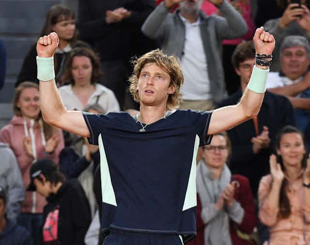 A tennis player raises his arms.