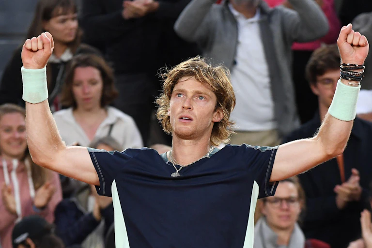 A tennis player raises his arms.