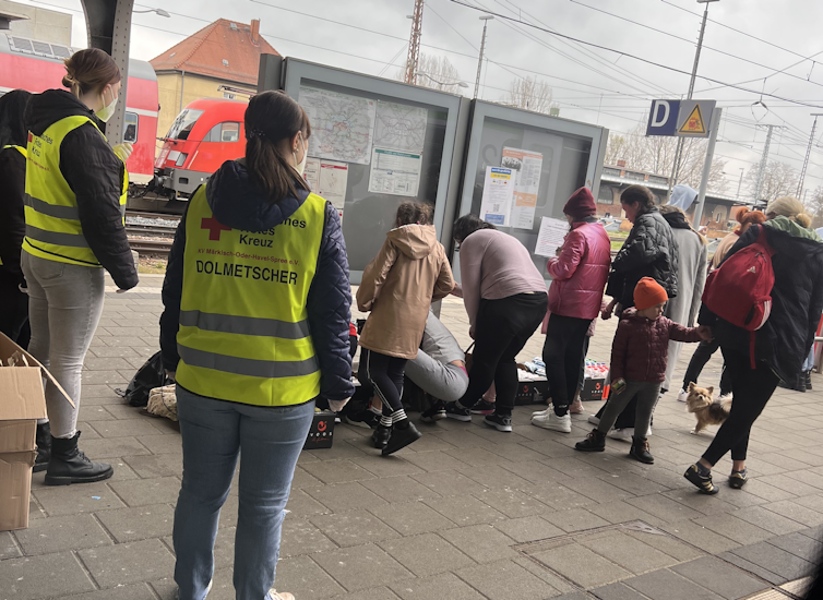 People are crowded around a sign at a train station