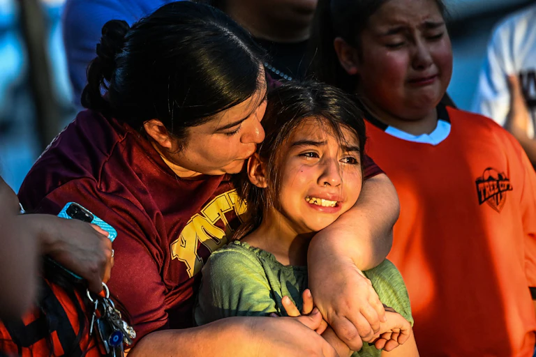 A young girl in tears is comforted an older woman who emvraces her.