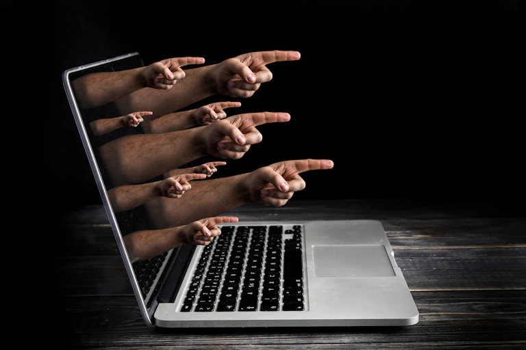 an open laptop with hands with pointing fingers emerging from the screen