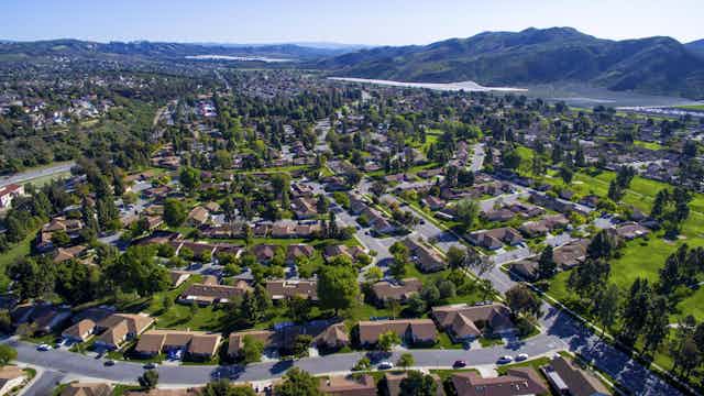 Aerial view of a suburban neighbourhood with mountains in the near distance. 
