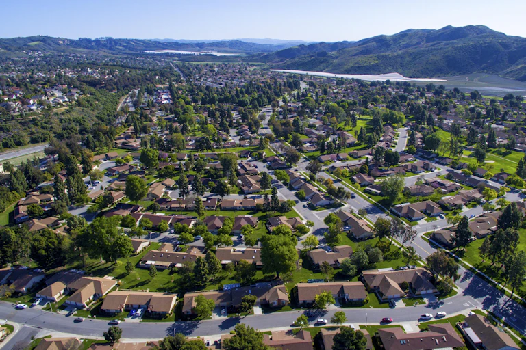 Aerial view of a suburban neighbourhood with mountains in the near distance.