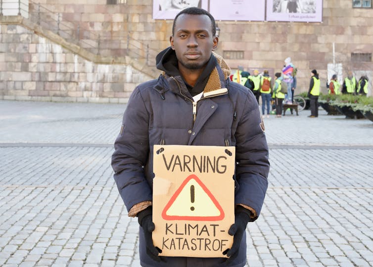 Man holds sign saying 'Varning: klimat-katastroph