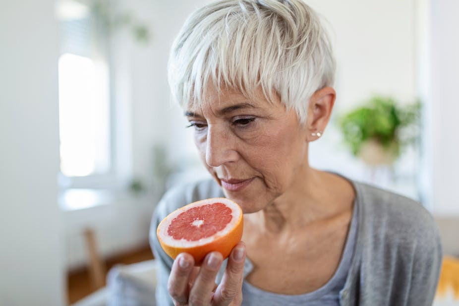 A woman smells a grapefruit.