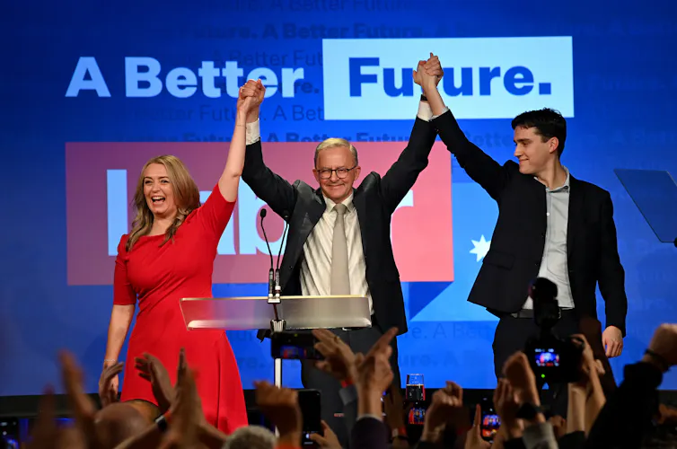 Anthony Albanese celebrating his election win on stage with his partner and son.