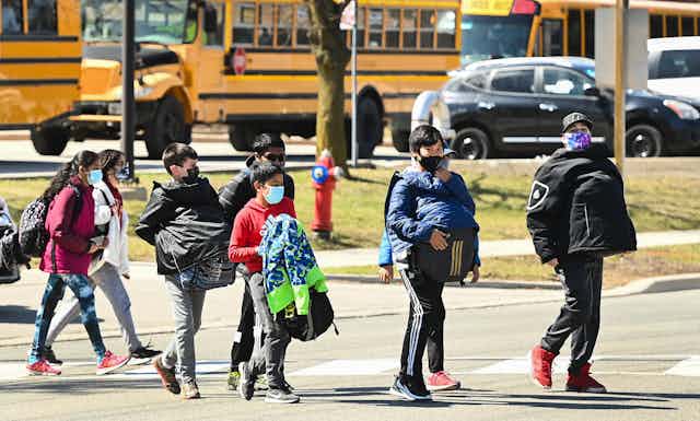 Children seen walking in front of a school bus.