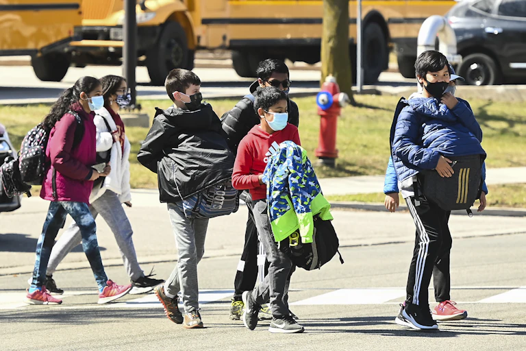 Children seen walking in front of a school bus.