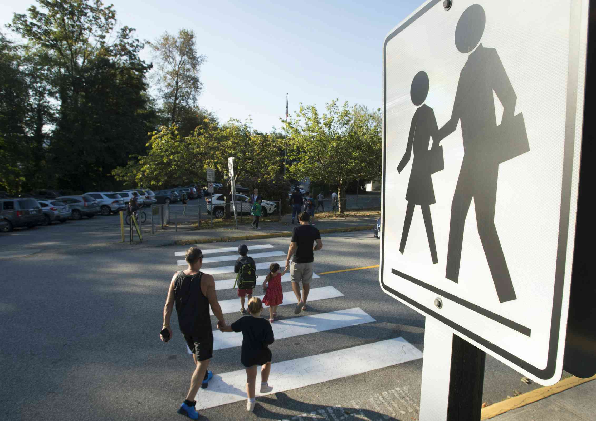 A parent and child seen at a crosswalk.