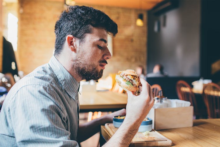 A man looks at a burger.