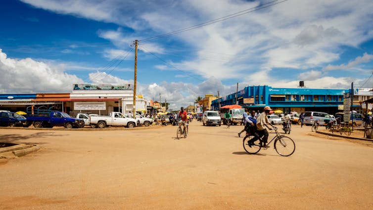 A dirt covered street with many cyclists.