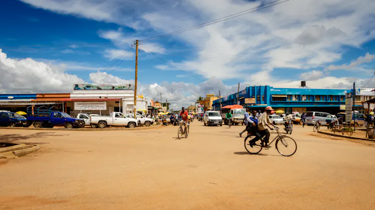 A dirt covered street with many cyclists.