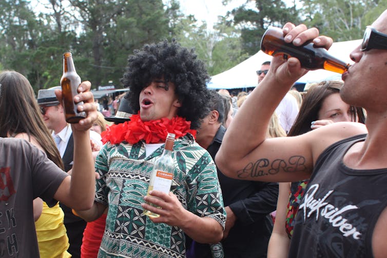 Man in costume drinks from wine bottle.