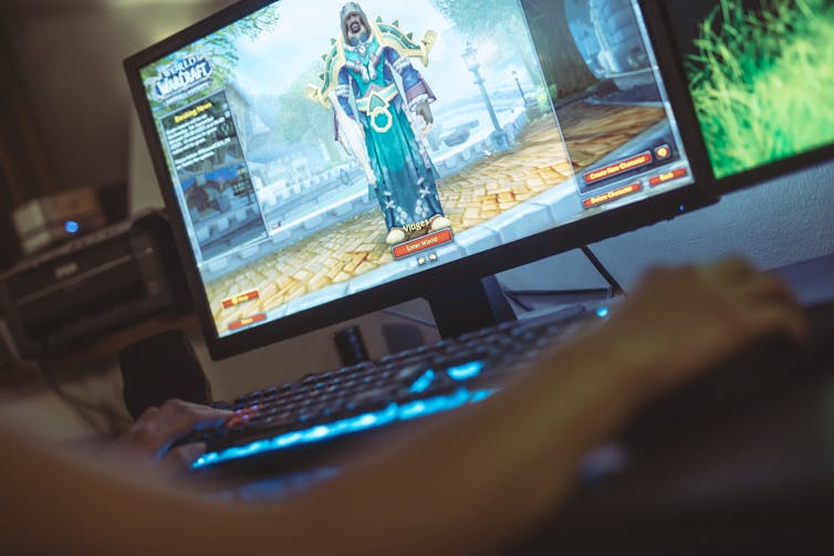 A gamer plays World of Warcraft on a PC, with just their arm and the screen visible.