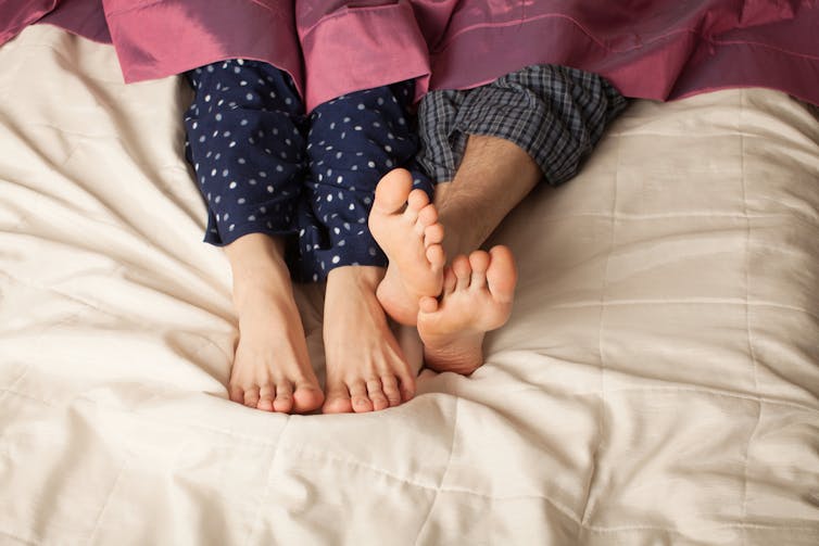 Deux paires de pieds sont côte à côte dans un lit