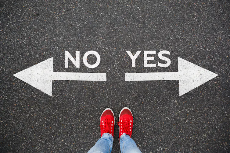 Bird's eye view of red shows and lower legs standing between two arrows, left for no and right for yes