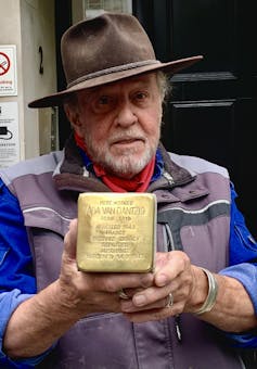 Man holds gold plaque.