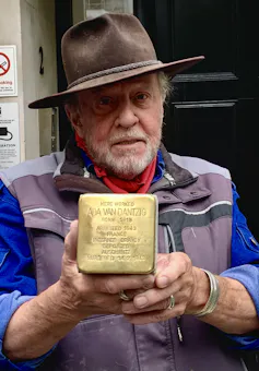 Man holds gold plaque.