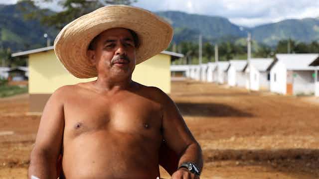Colombian former guerrilla soldier in front of simple huts