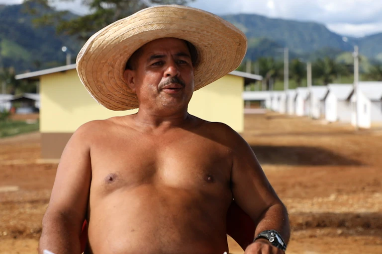 Colombian former guerrilla soldier in front of simple huts