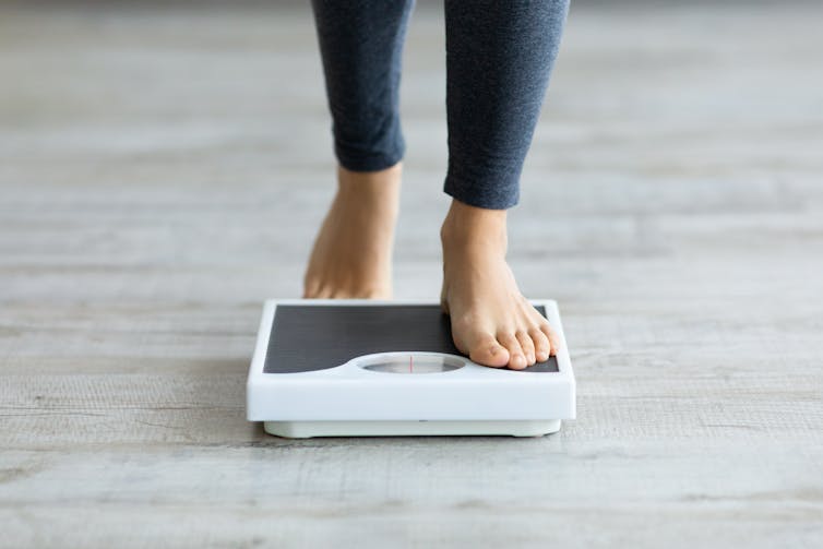 a person steps onto a scale to weigh themselves.