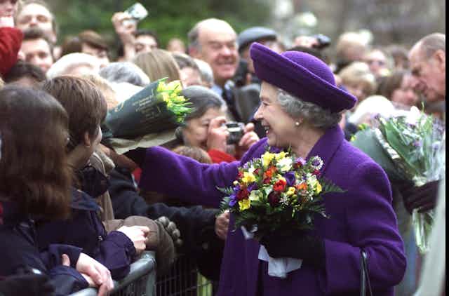 Queen recieves flowers from crowd. 
