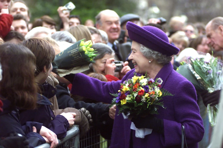 Queen recieves flowers from crowd.