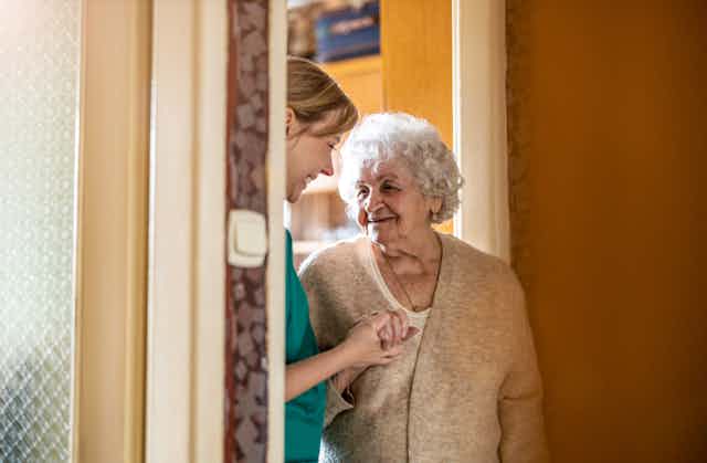 Photo d’une femme âgée chez elle avec une soignante