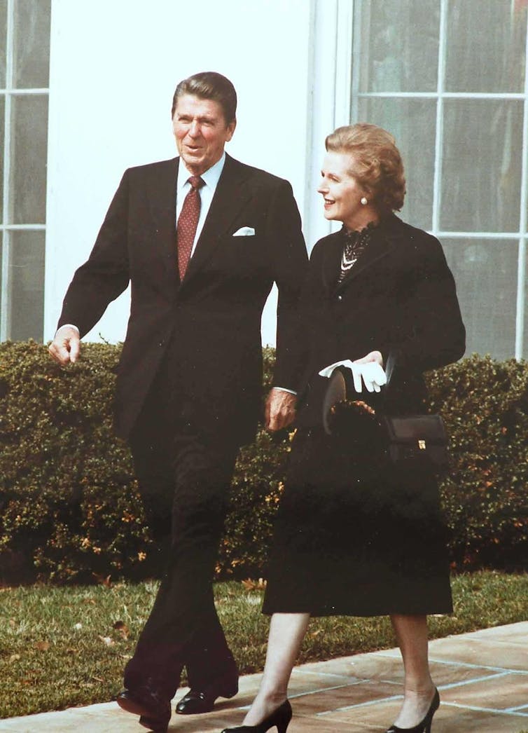 Ronald Reagan and Margaret Thatcher walk side by side outside of the White House