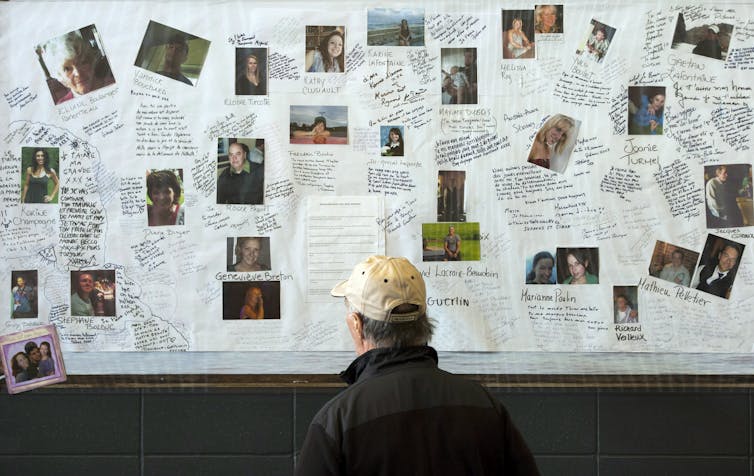 A man looking at a bulletin board covered in photos and scraps of writing